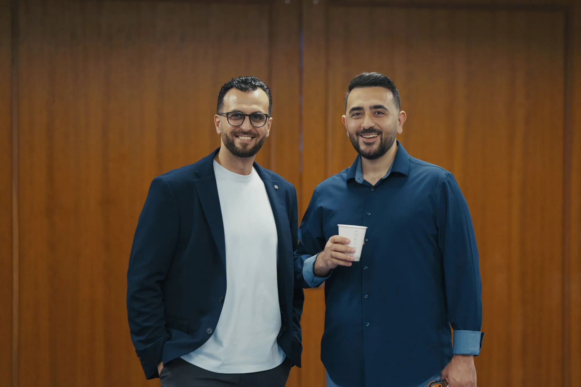 Two guests smiling together for a professional portrait at an event