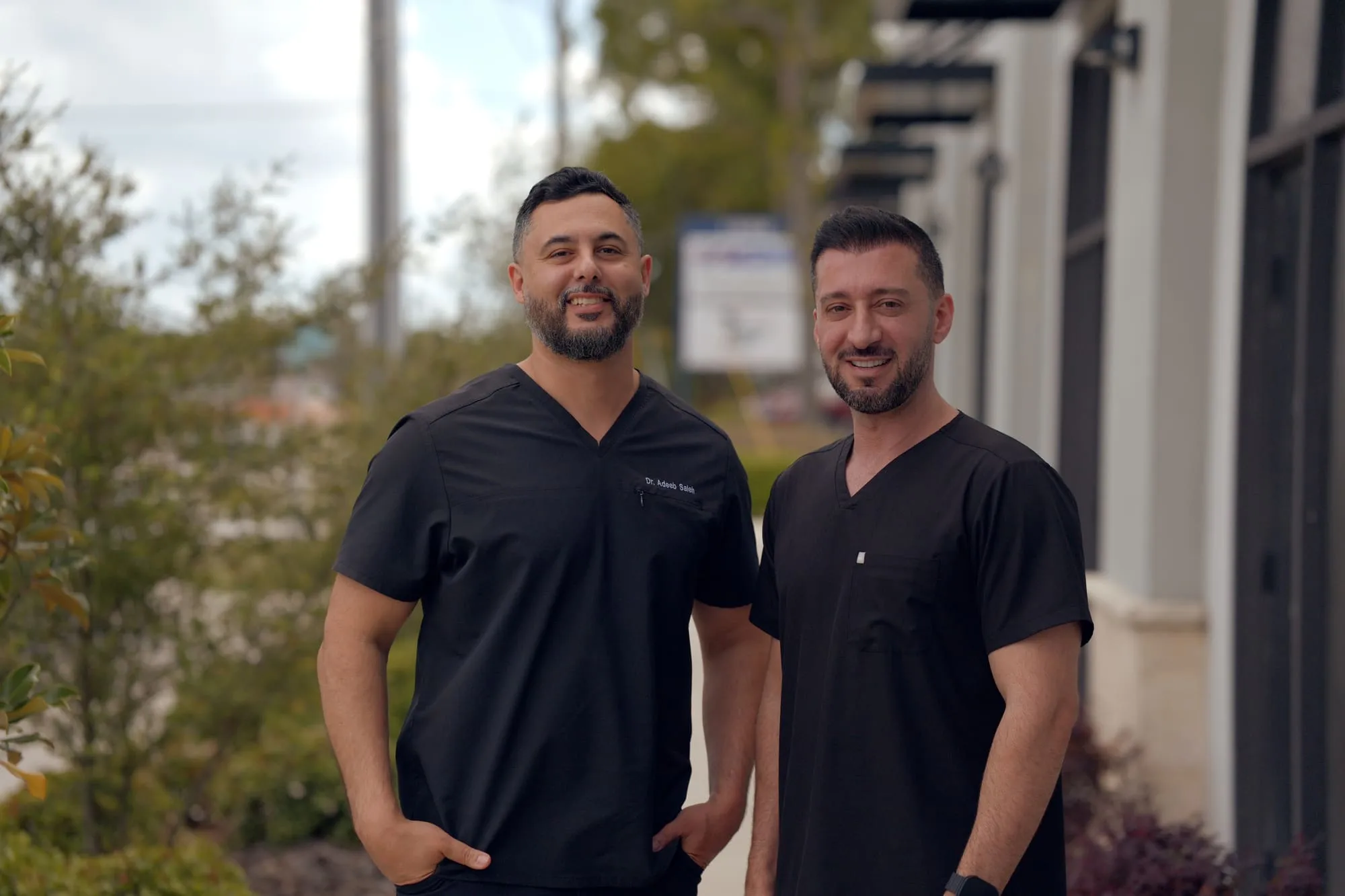 Full-length outdoor portrait of two medical professionals wearing black scrubs