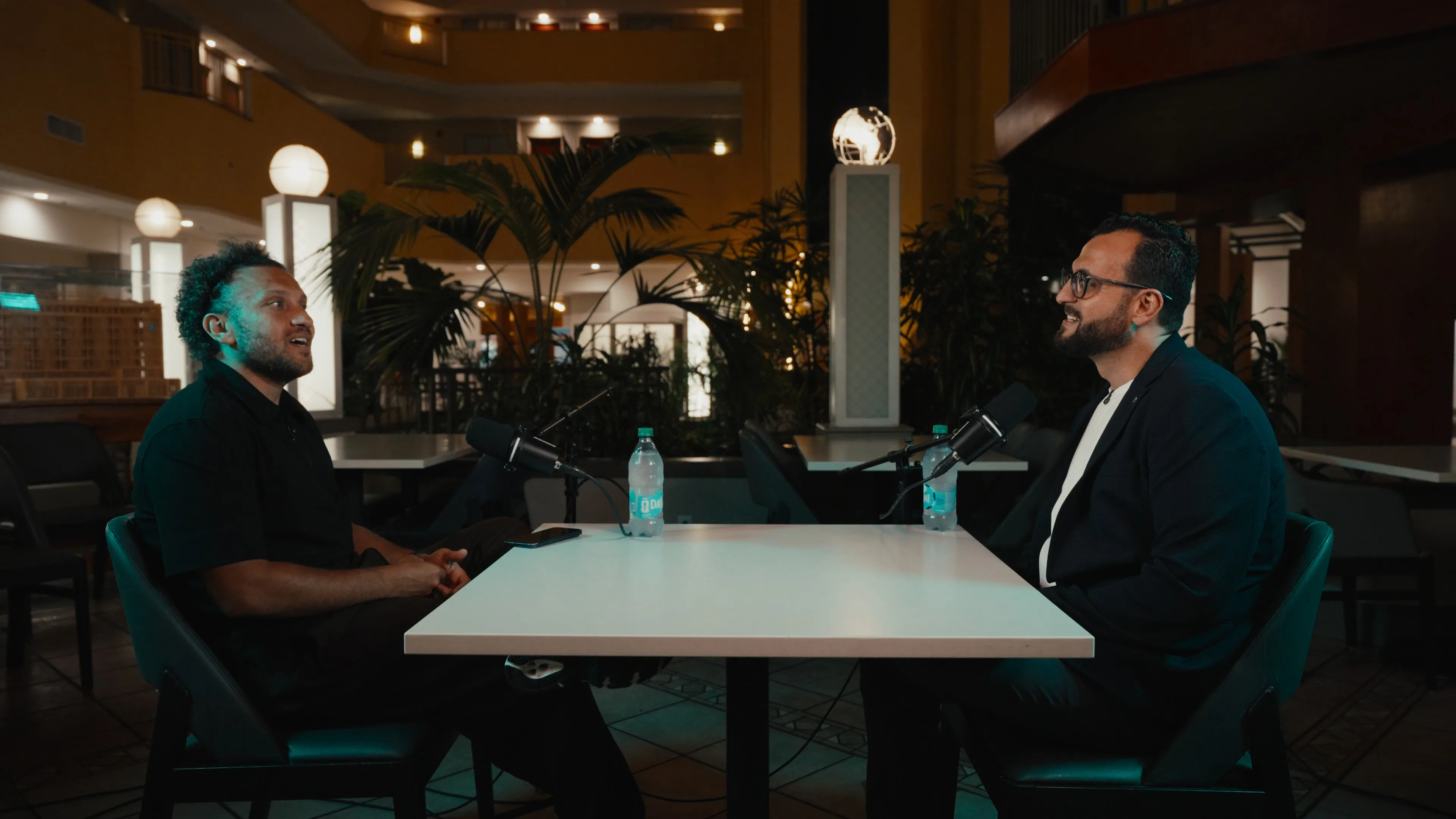 Youssef Hussein and Haithum smiling across the podcast table in the Embassy Suites Tampa USF atrium
