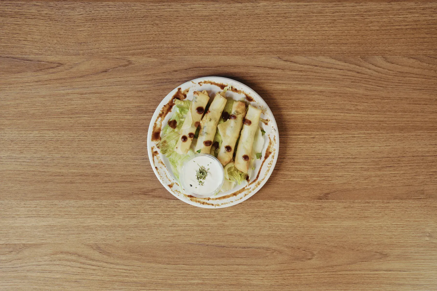 Cheese rolls arranged over lettuce with a side of dipping sauce