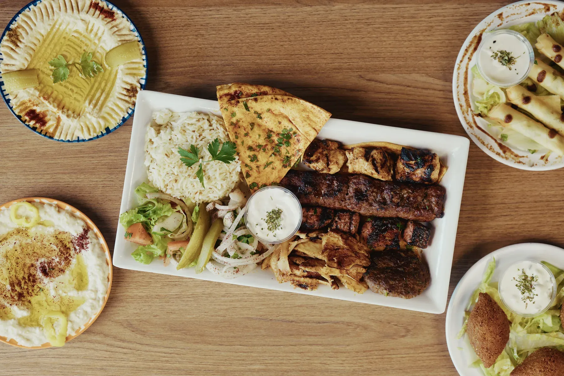 Mixed grill platter with chicken, beef, kafta, rice, salad, pita bread, hummus, and appetizers