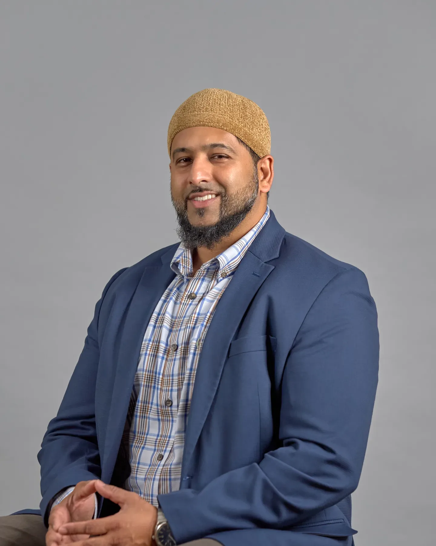 Bayaan Academy staff member wearing a blue jacket against a gray portrait background